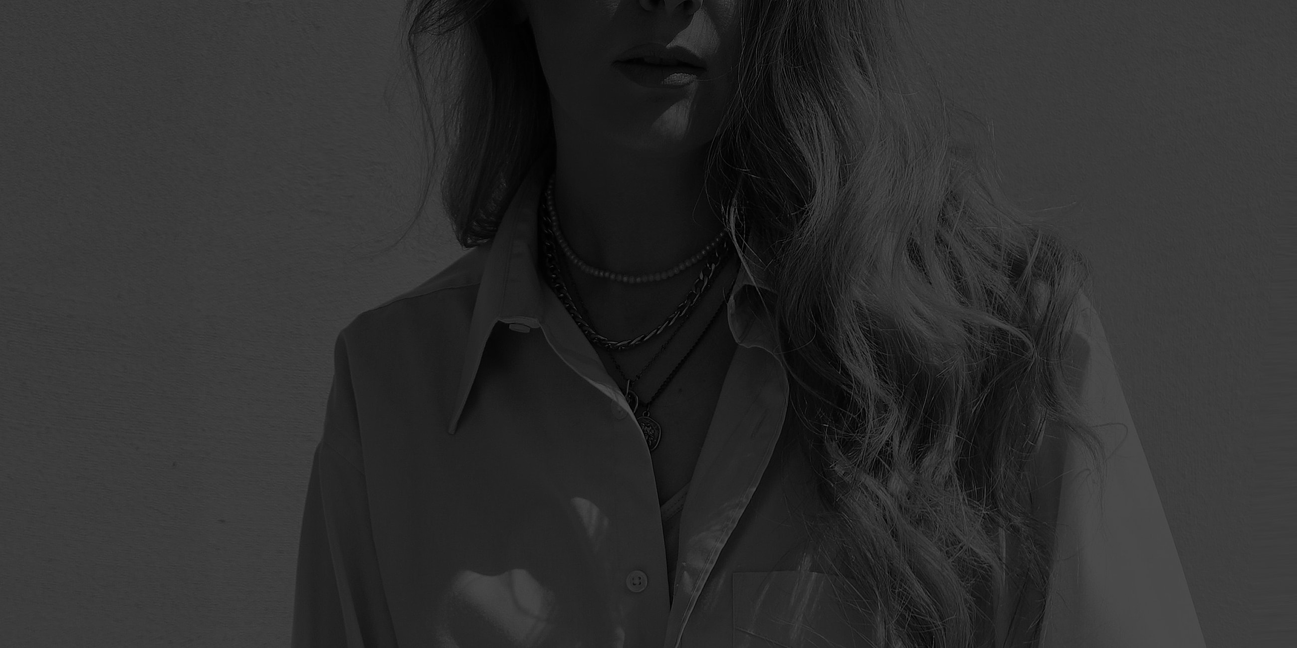 NYC plastic surgery model wearing layered necklaces and a shirt.