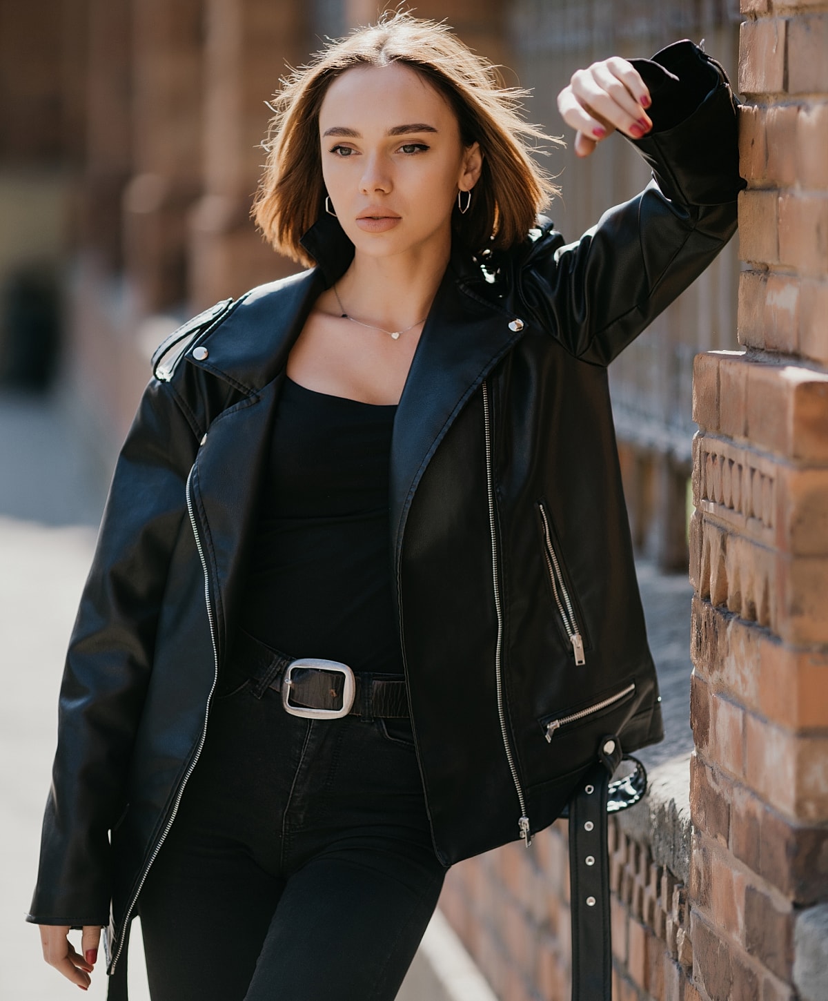 NYC cosmetic plastic surgery model in black leather jacket posing outdoors.