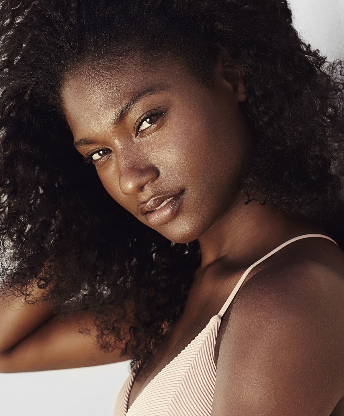 Young woman with curly hair, looking confidently at camera.
