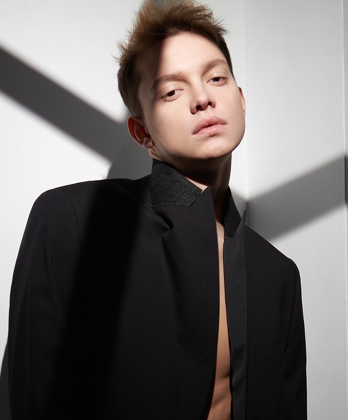Model in black jacket with dramatic lighting.