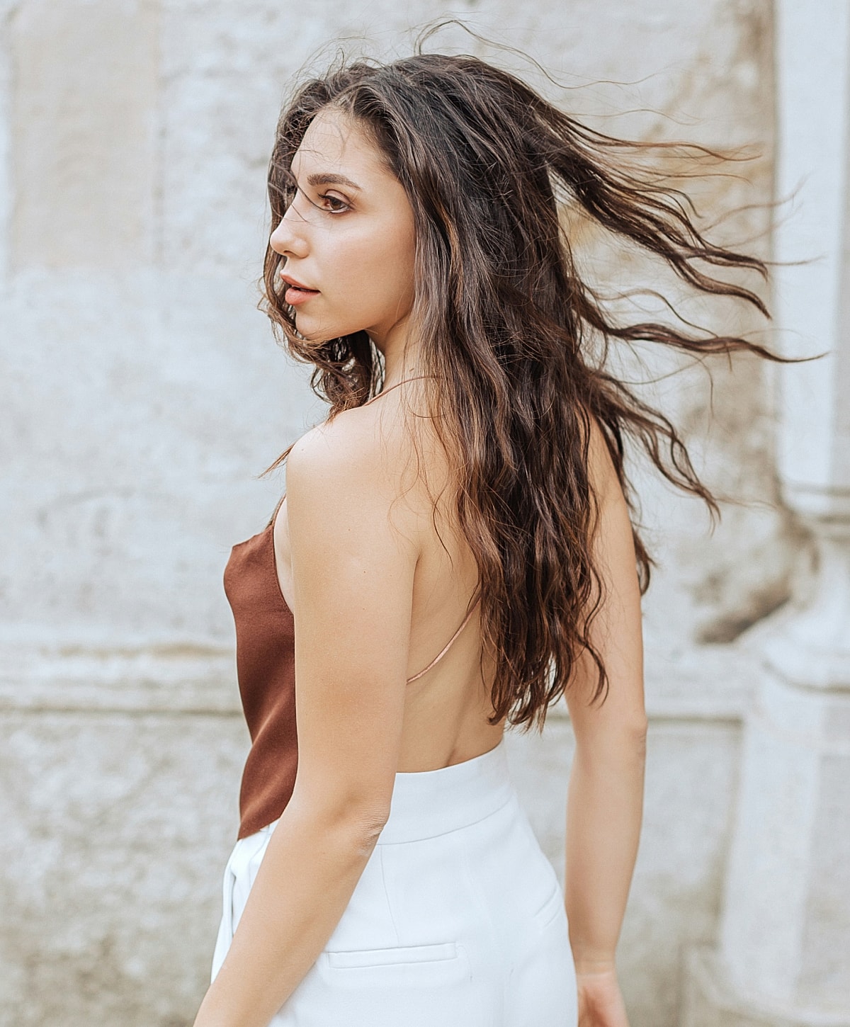 NYC Keloid and Scar Revision model with long hair against stone background.