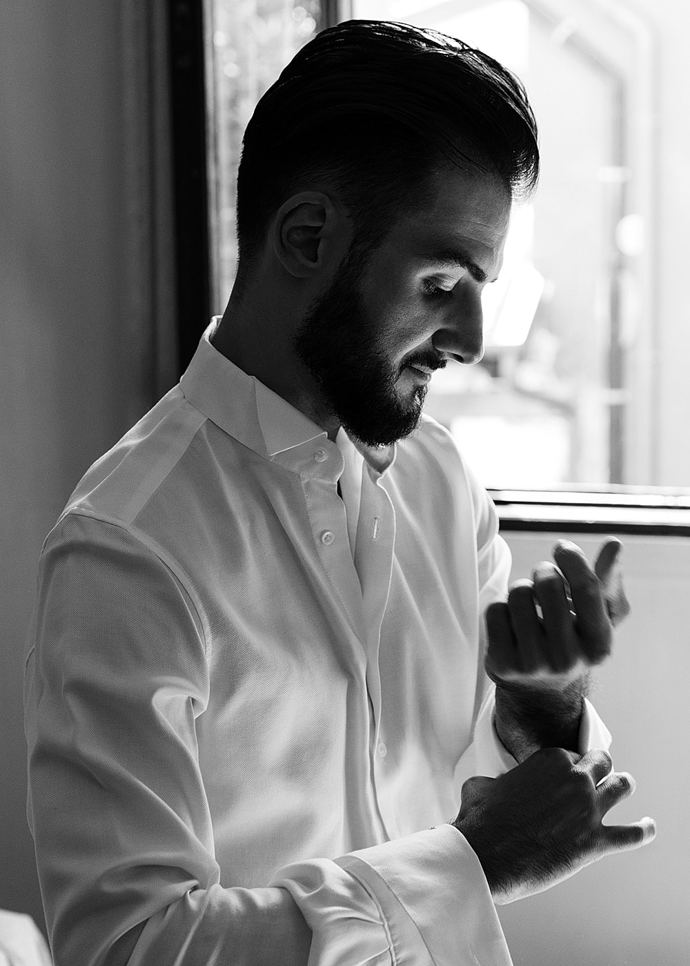 NYC plastic surgery model adjusting cuffs in a black and white photo.