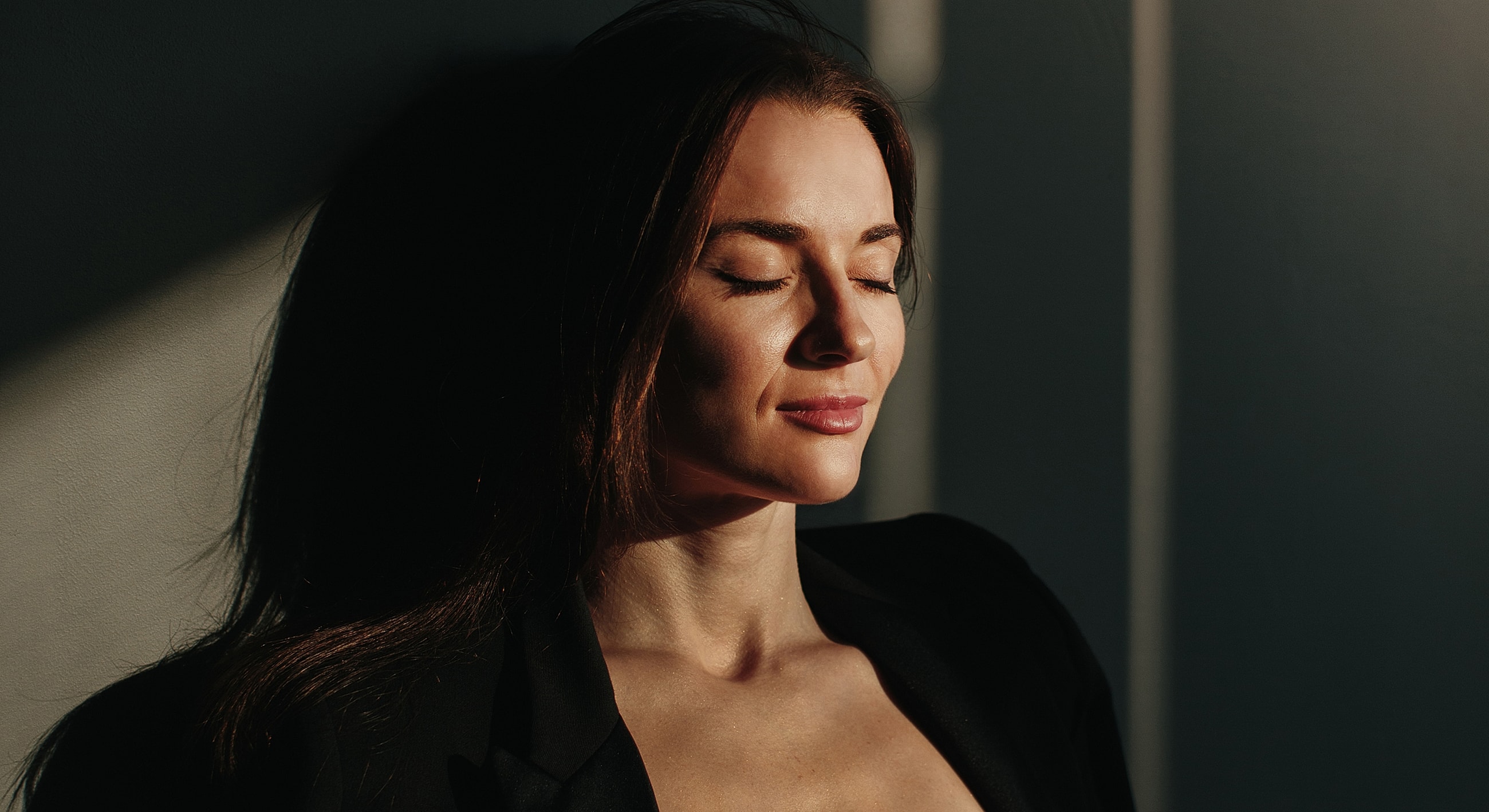 Woman with closed eyes in soft sunlight.