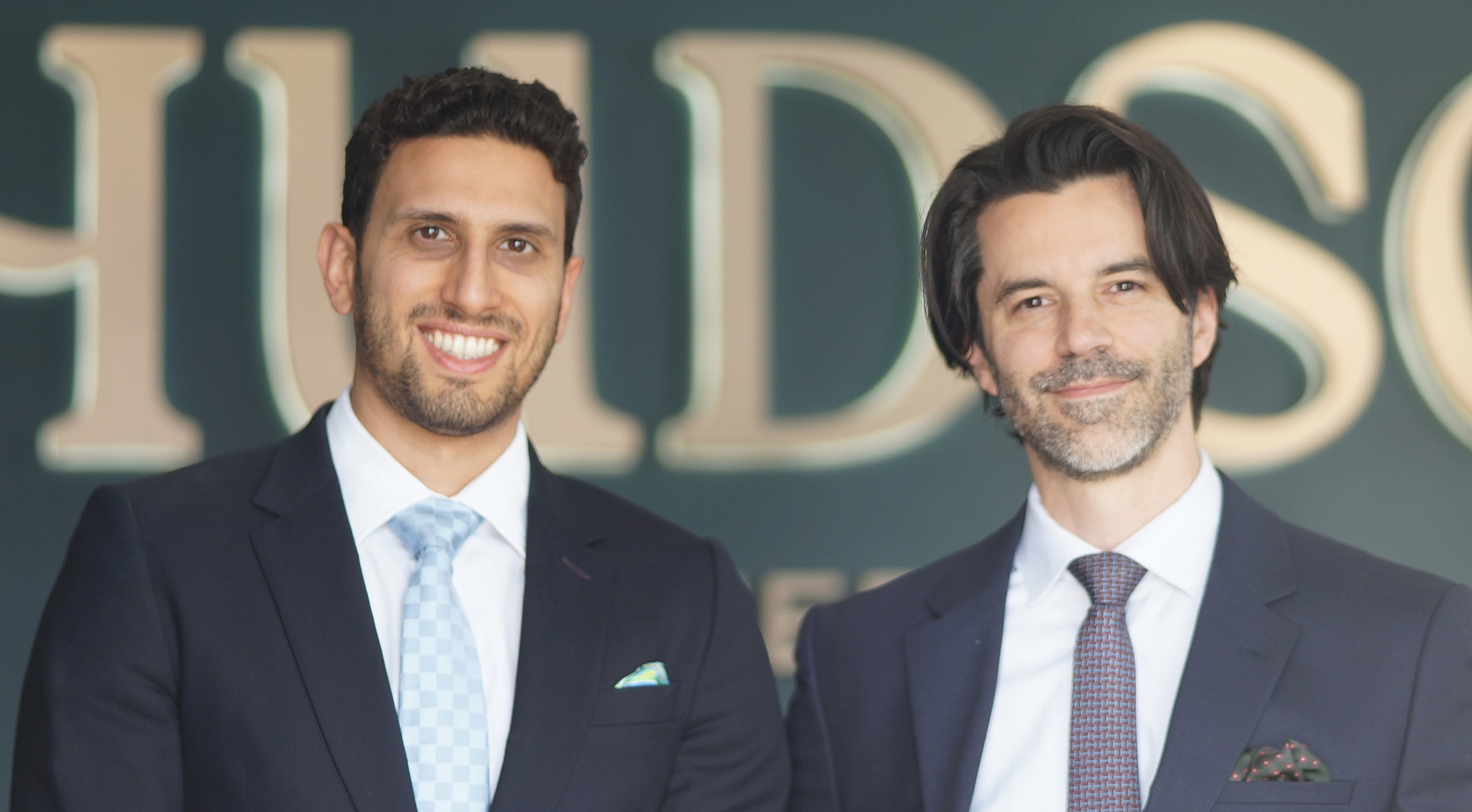 NYC plastic surgeons smiling in front of business sign.